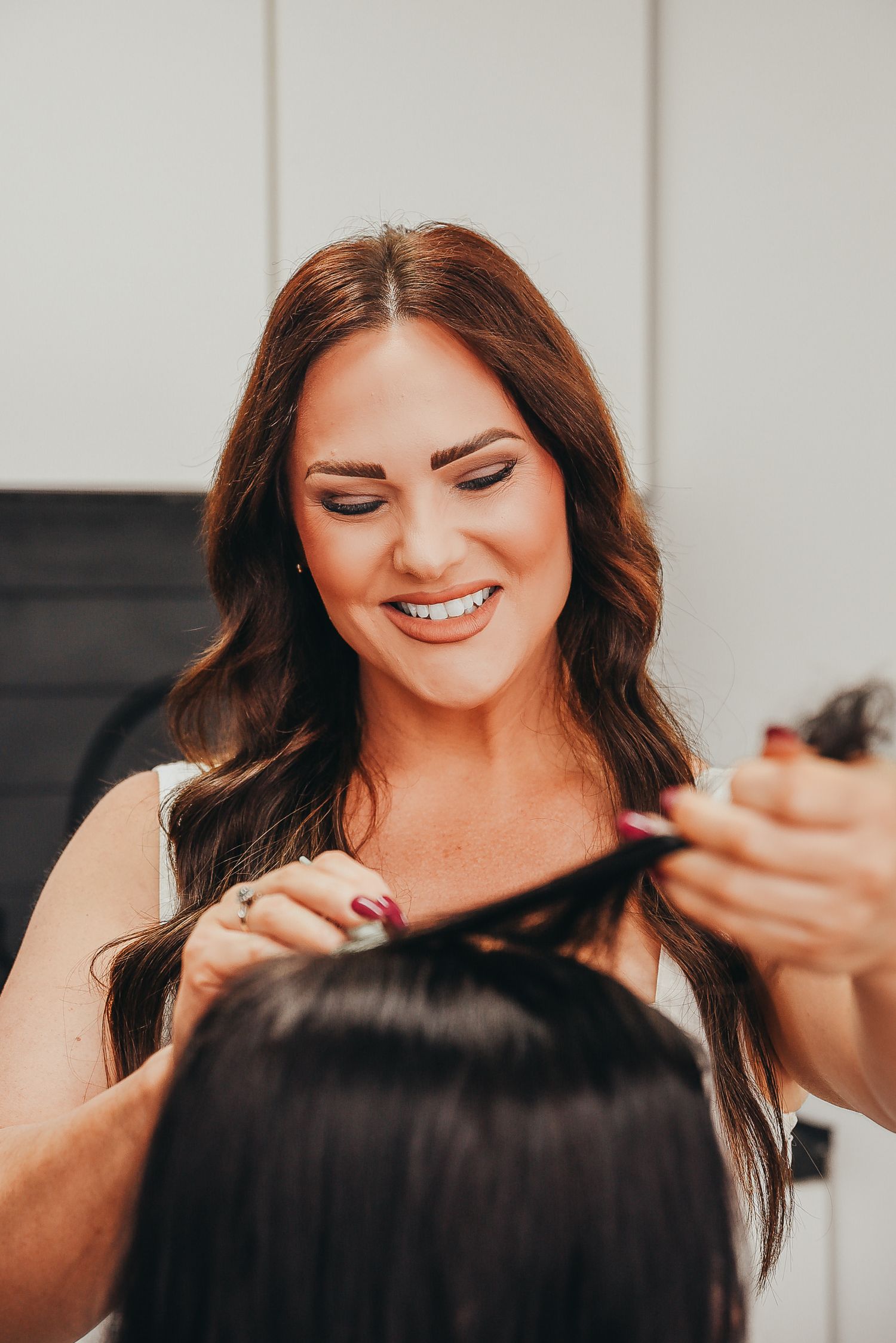 Hair stylist smiling while working on client's hair in salon.