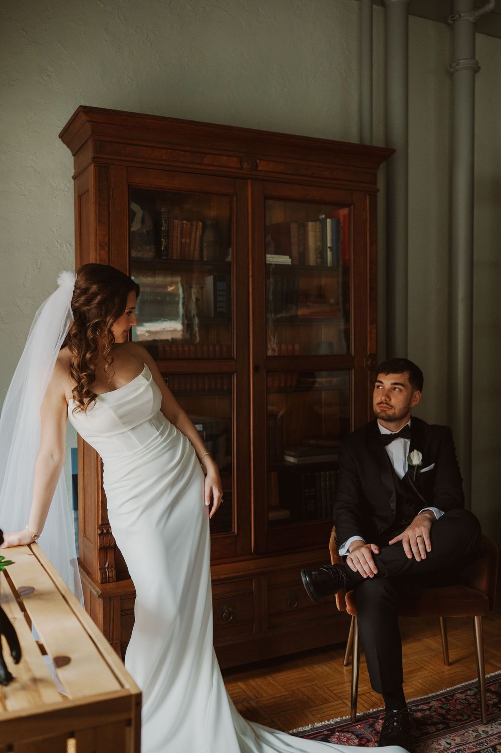 A sequence of playful wedding photos showing a bride in white dress interacting with someone near wooden cabinets.