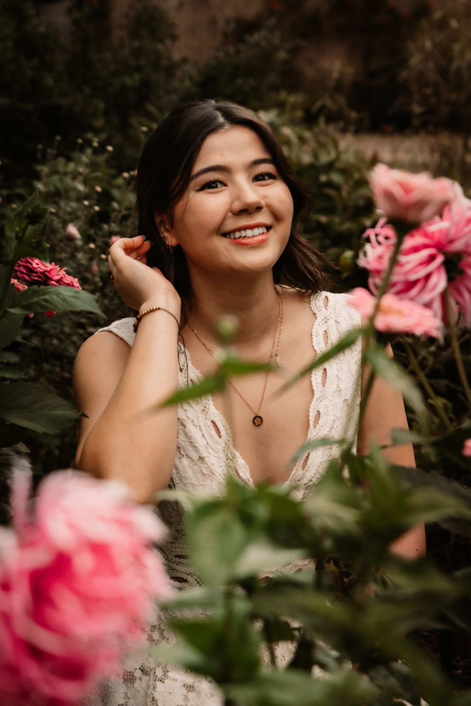 Pink roses frame a romantic garden portrait scene with soft natural lighting and lush greenery.