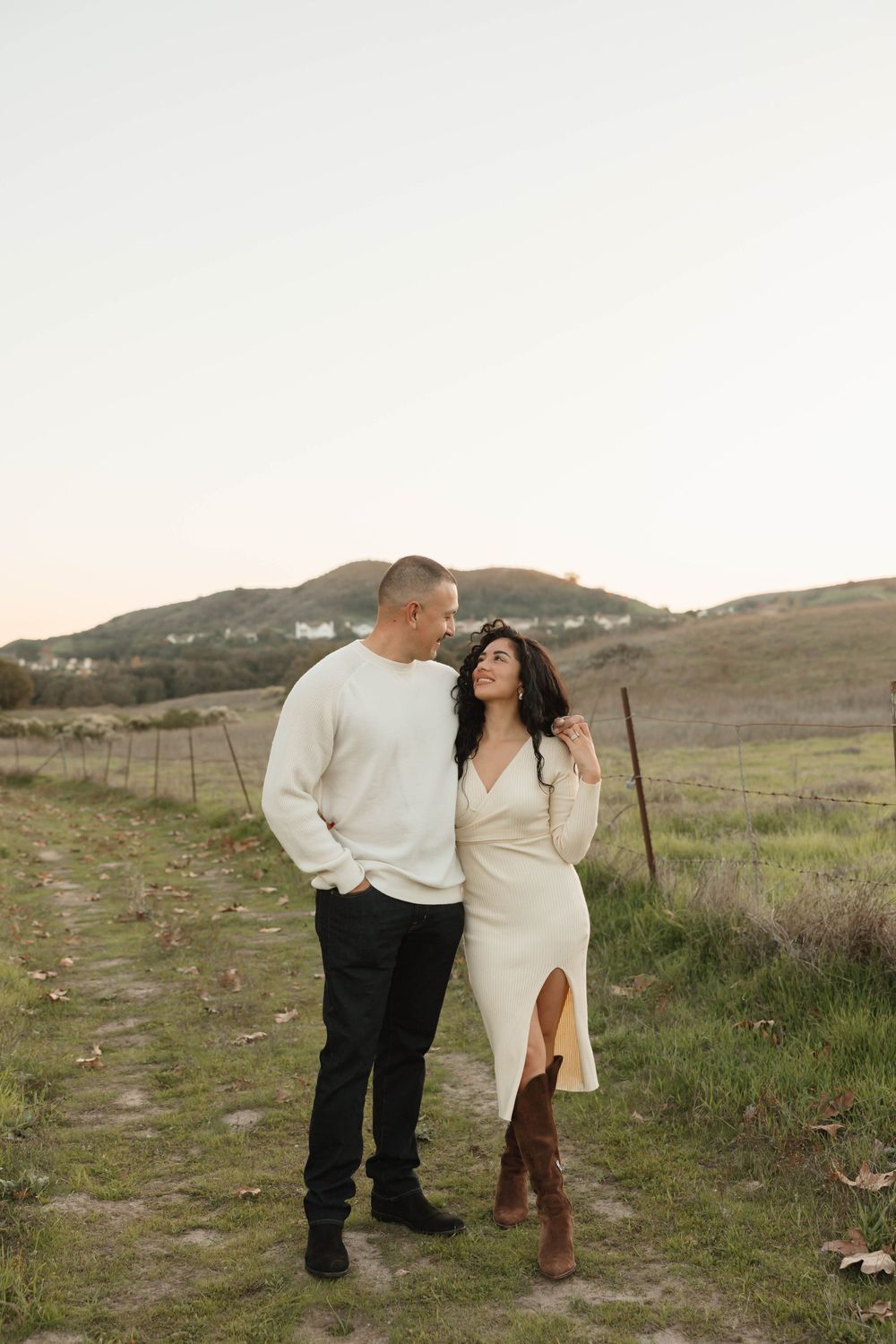 A couple shares a tender moment together on a hillside path surrounded by natural scenery.