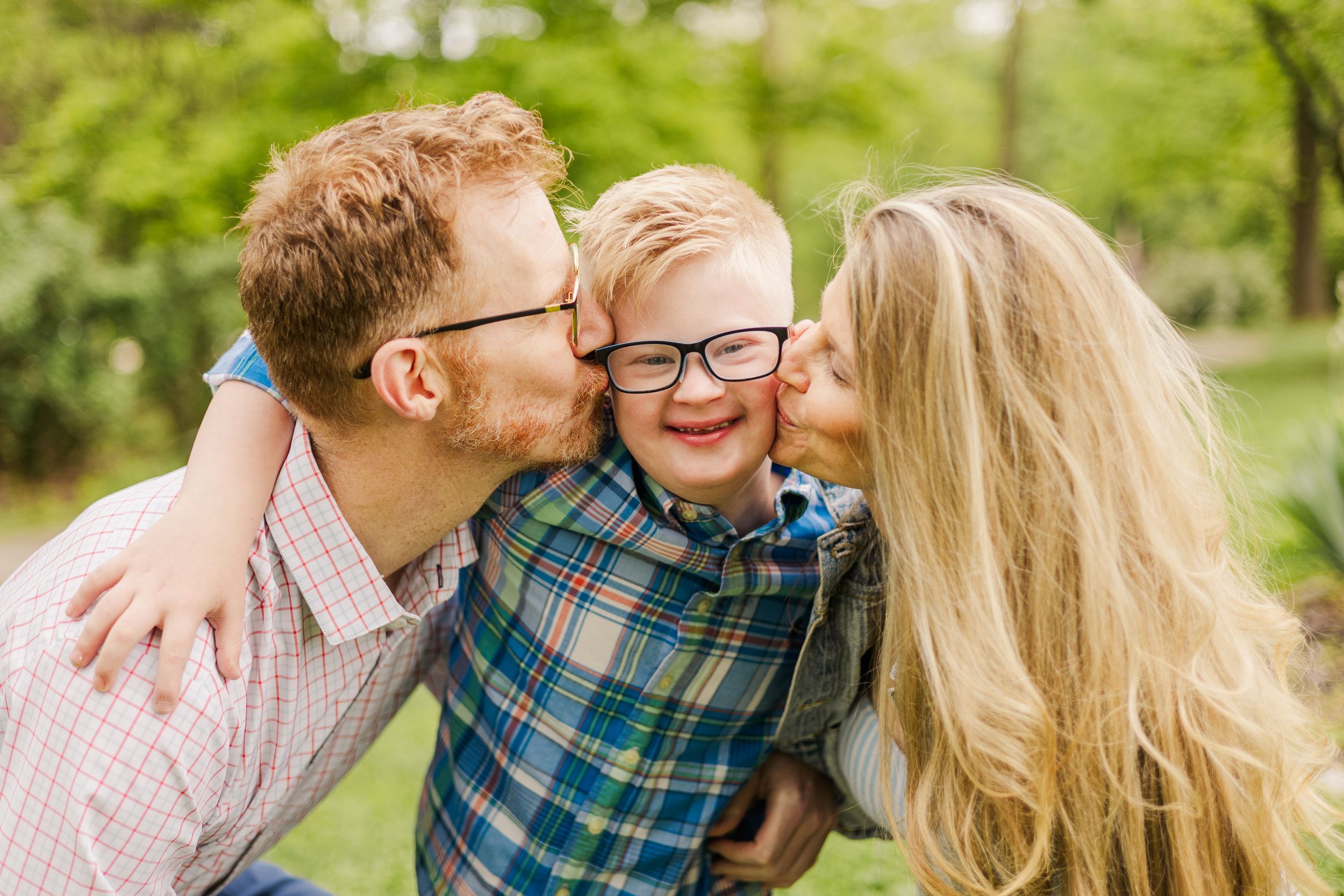 Joyful outdoor family moment captured in natural lighting with green foliage background.