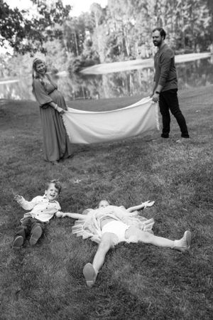 A black and white photo by B. Logsdon shows two children lying in grass while parents hold up a white blanket at the park in Savannah, GA.