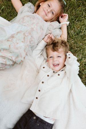 Photo by B.Logsdon of two young children lying on green grass sharing a joyful moment together in Bluffton, South Carolina.