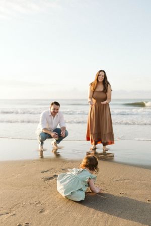 Photo by B.Logsdon of a family spending time together on a sandy beach on HHI at sunset as waves roll in along the shoreline.