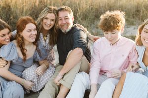A family sits together on the ground during a golden hour photoshoot with B.Logsdon photography at Hilton Head Island, South Carolina.