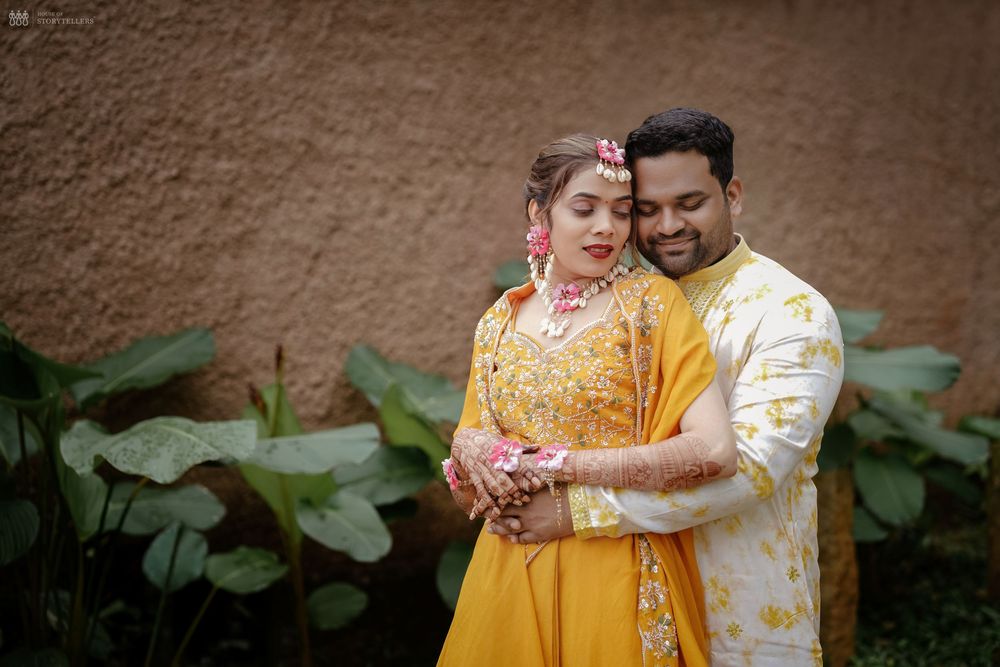 Indian couple in yellow traditional attire embracing during a Haldi pre-wedding ceremony outdoors.