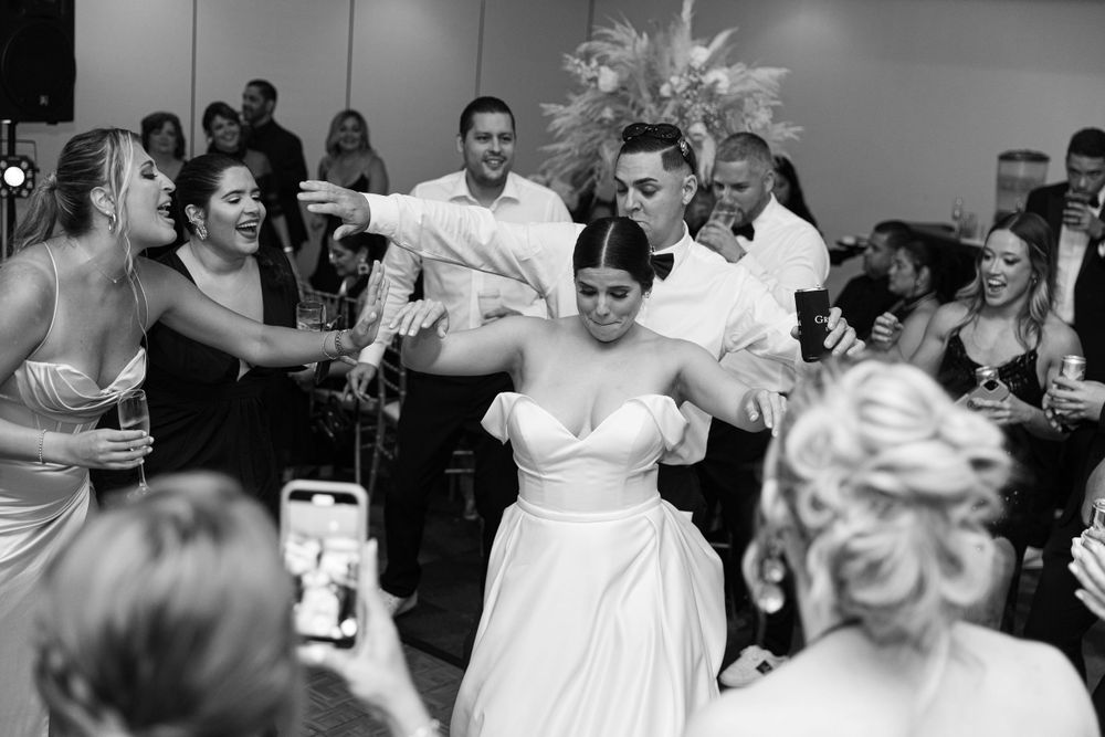 Energetic dance floor scene at wedding reception with guests celebrating.