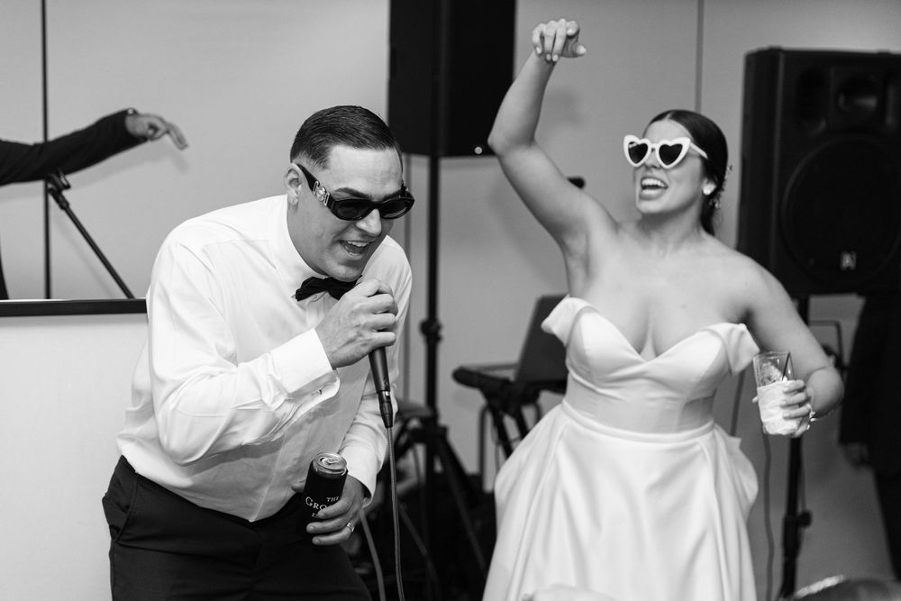 Wedding party members singing and dancing enthusiastically during reception celebration.