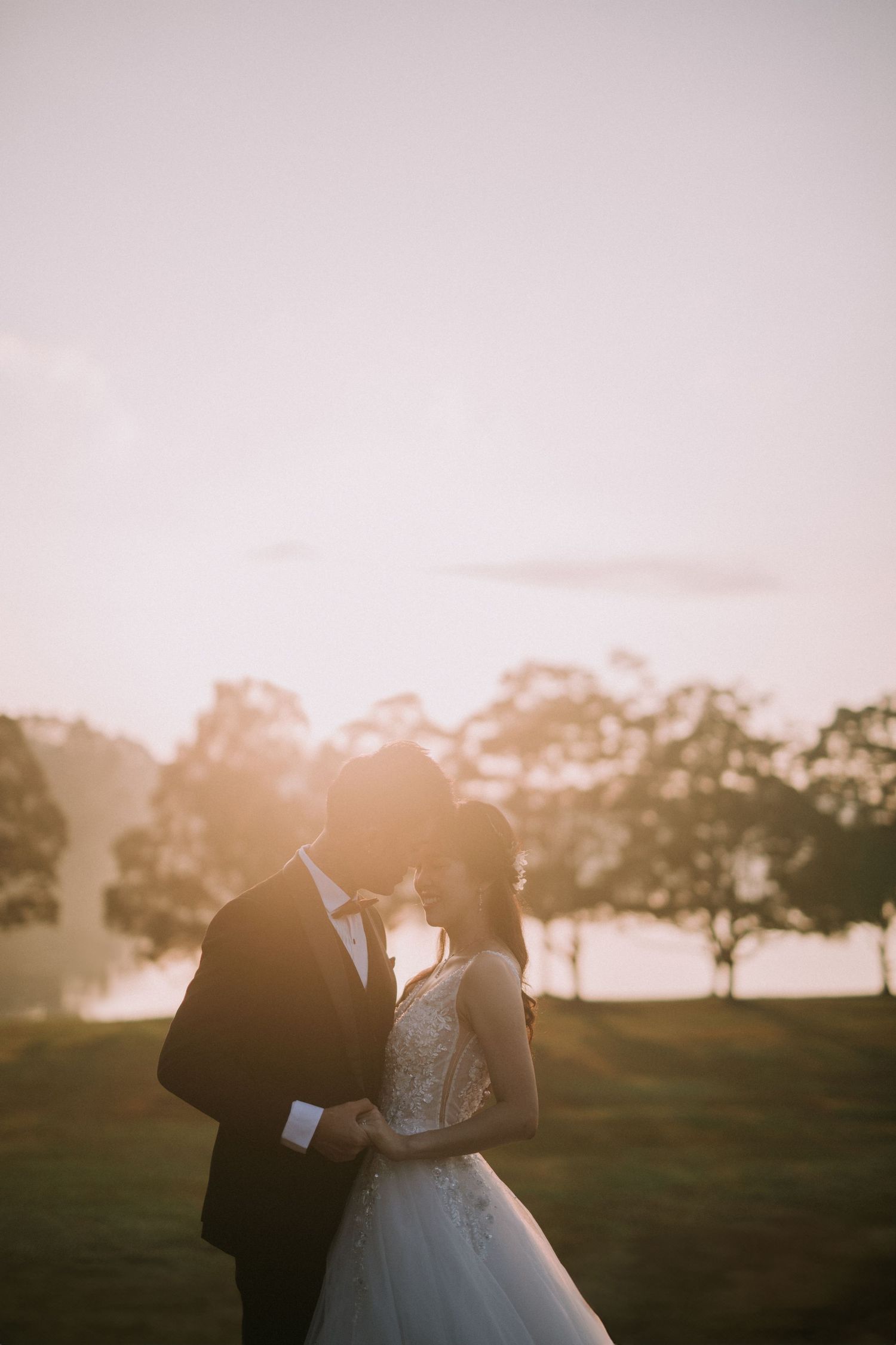 A couple shares an intimate moment during their sunset wedding photoshoot in a park setting.