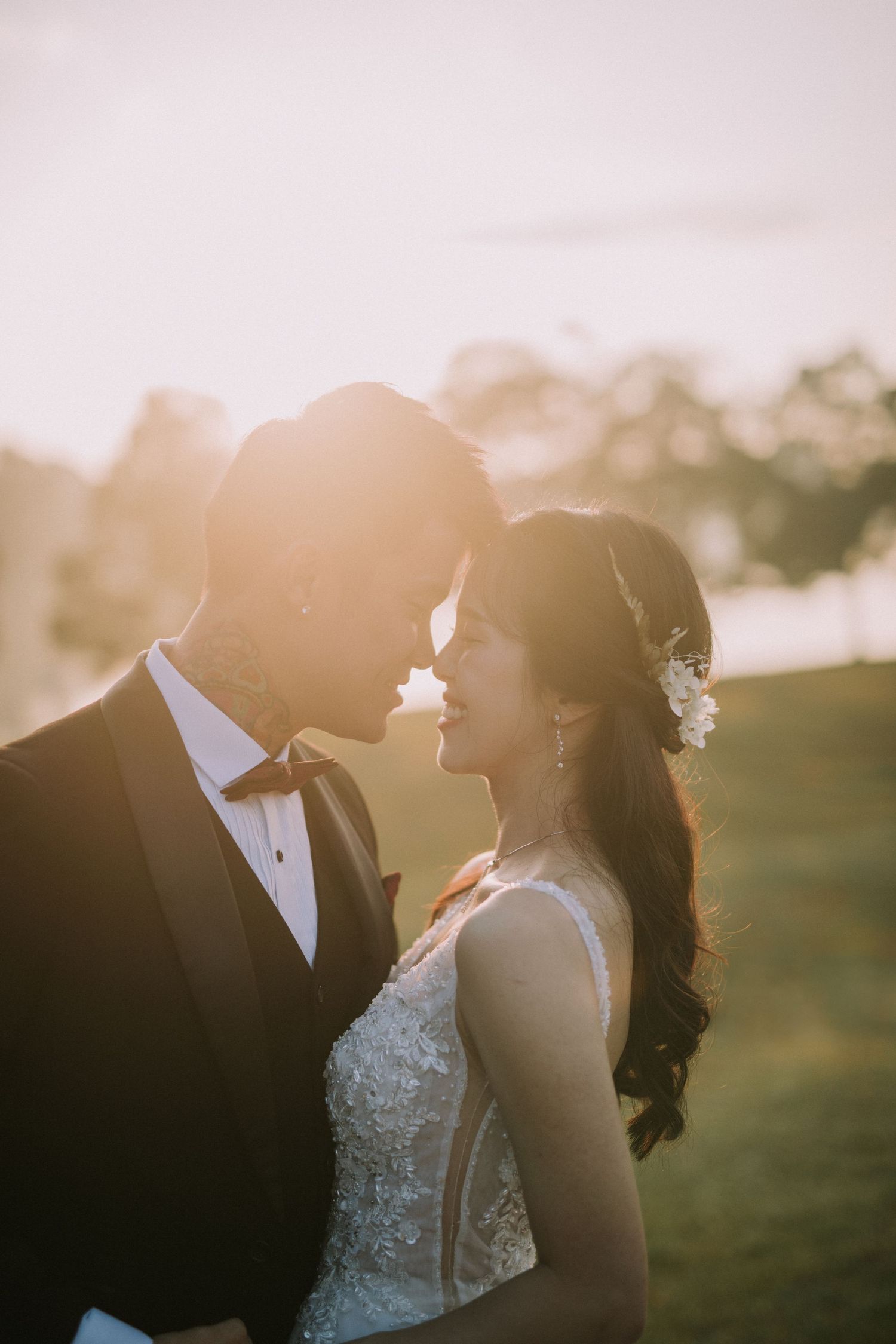 A wedding couple shares a tender moment in warm sunset lighting.