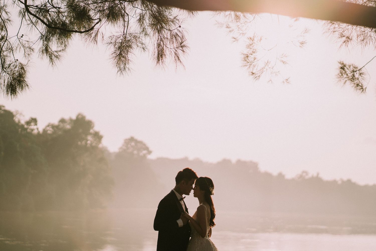 Silhouettes of a wedding couple against a dreamy sunset backdrop.