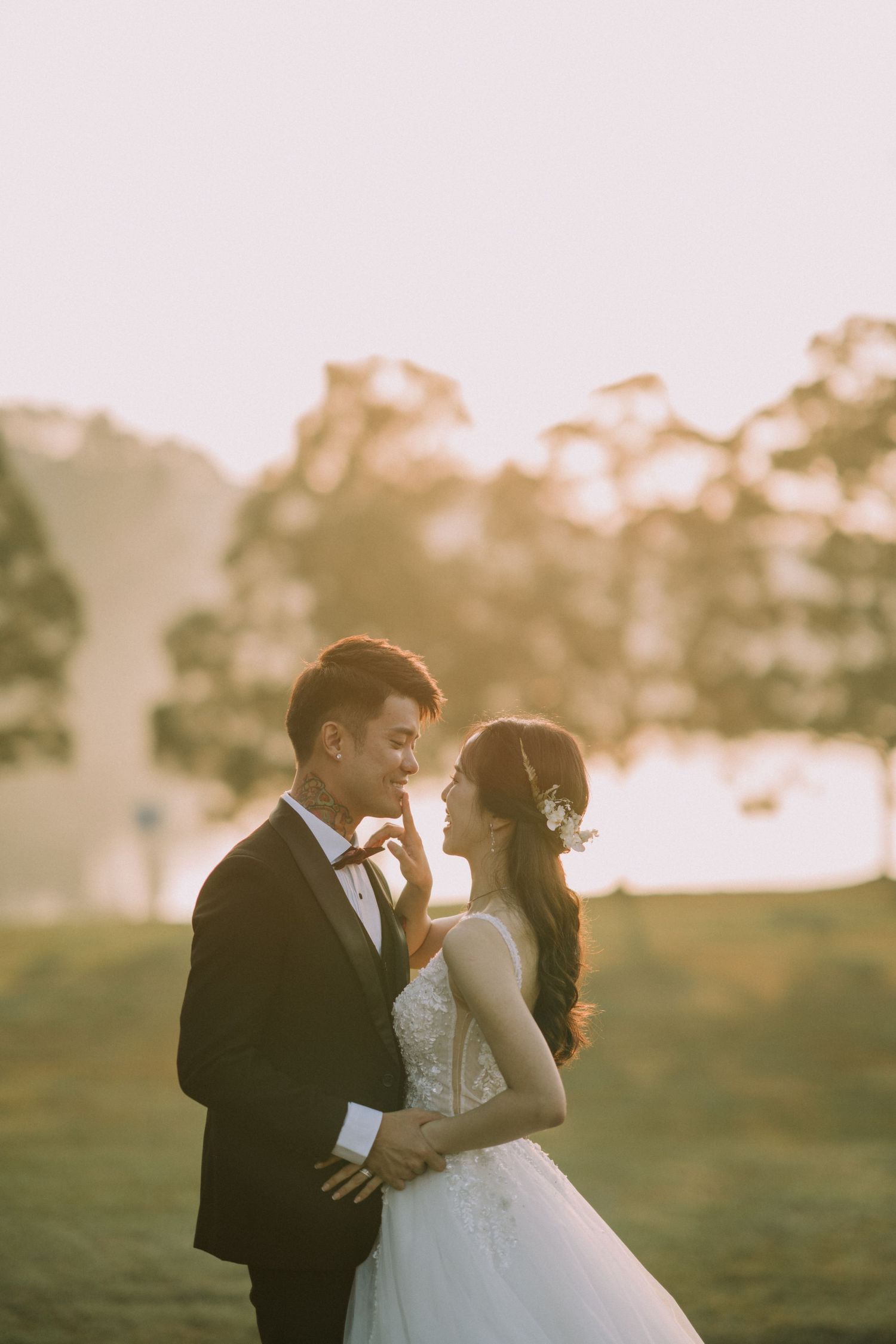 A romantic wedding photoshoot in a field during sunset with soft golden lighting.