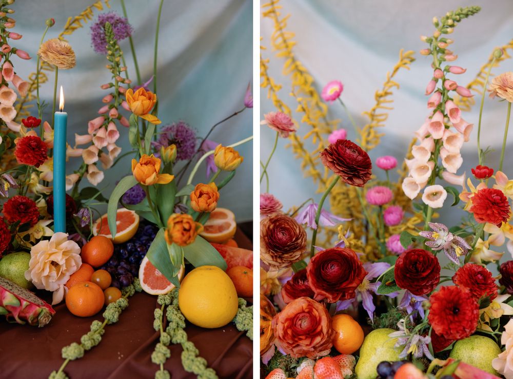 Colorful floral display with citrus fruits, foxgloves, and roses alongside a blue taper candle.
