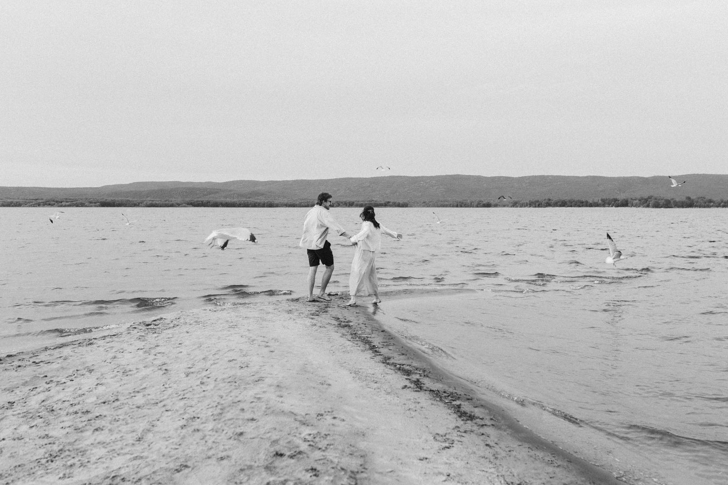 Two young siblings embracing while looking out at the calm water.
