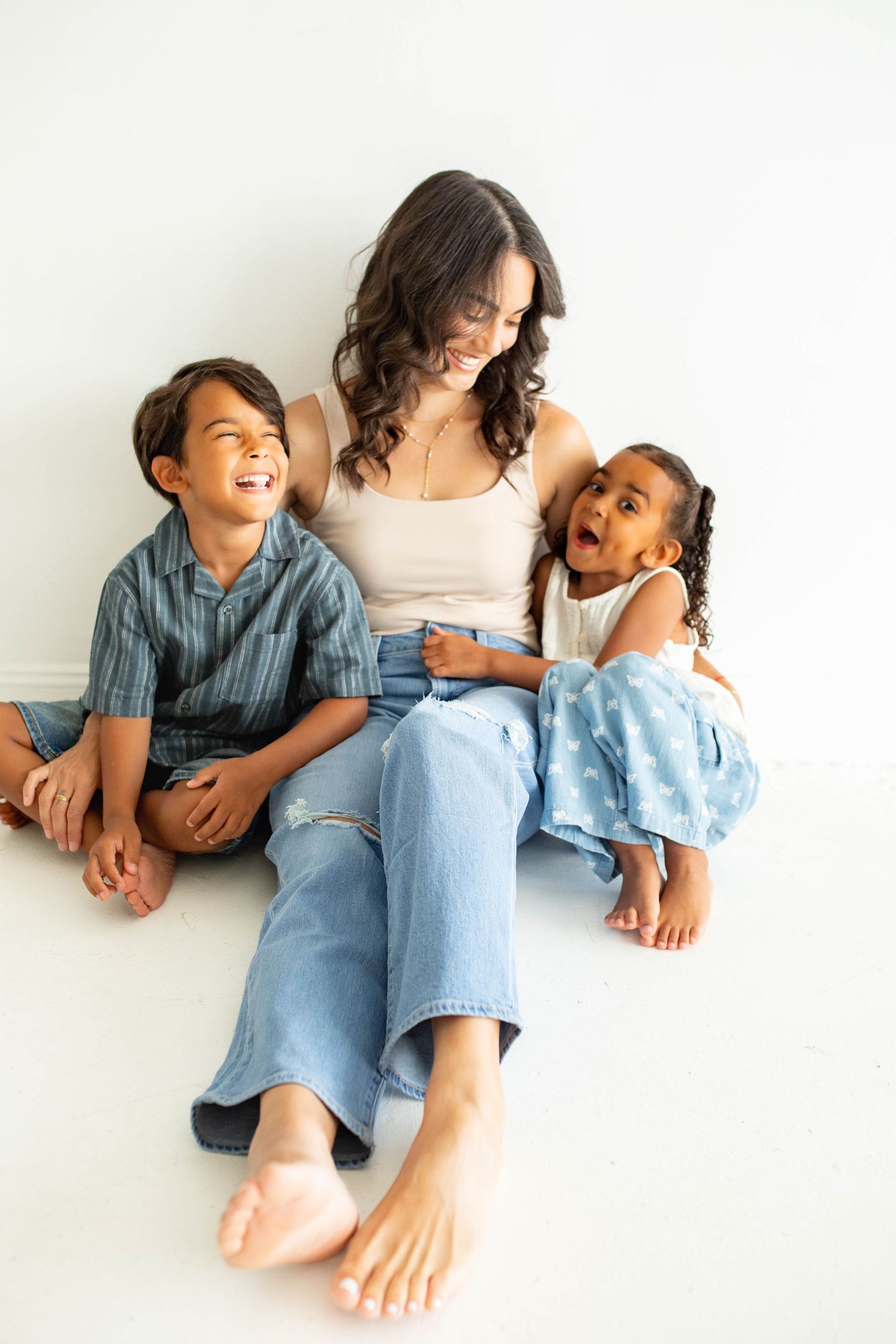 A sweet candid photo series showing playful family moments of a parent and children lounging together in casual denim.