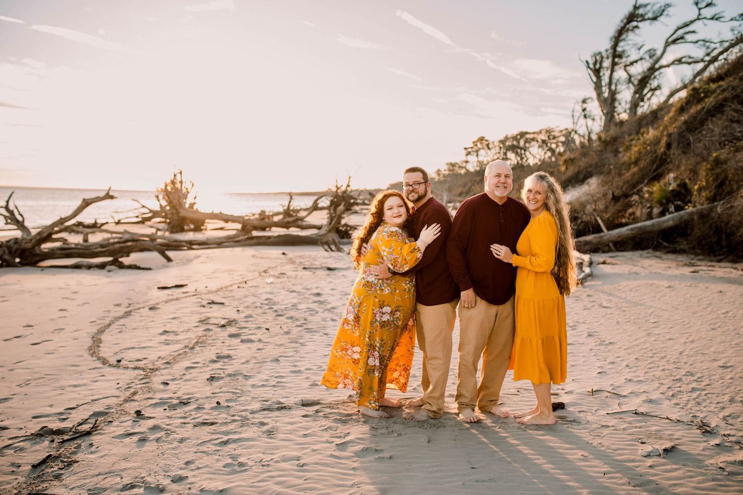 Group in coordinated yellow and black outfits poses on sunset beach with driftwood.