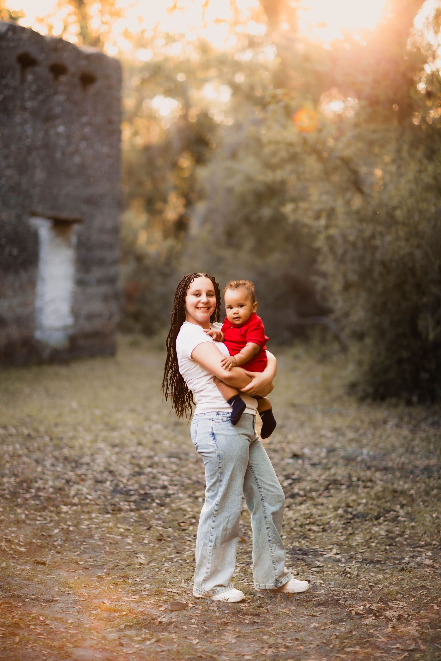 A warm sunset photo in a natural outdoor setting with a white stone wall and trees in the background.