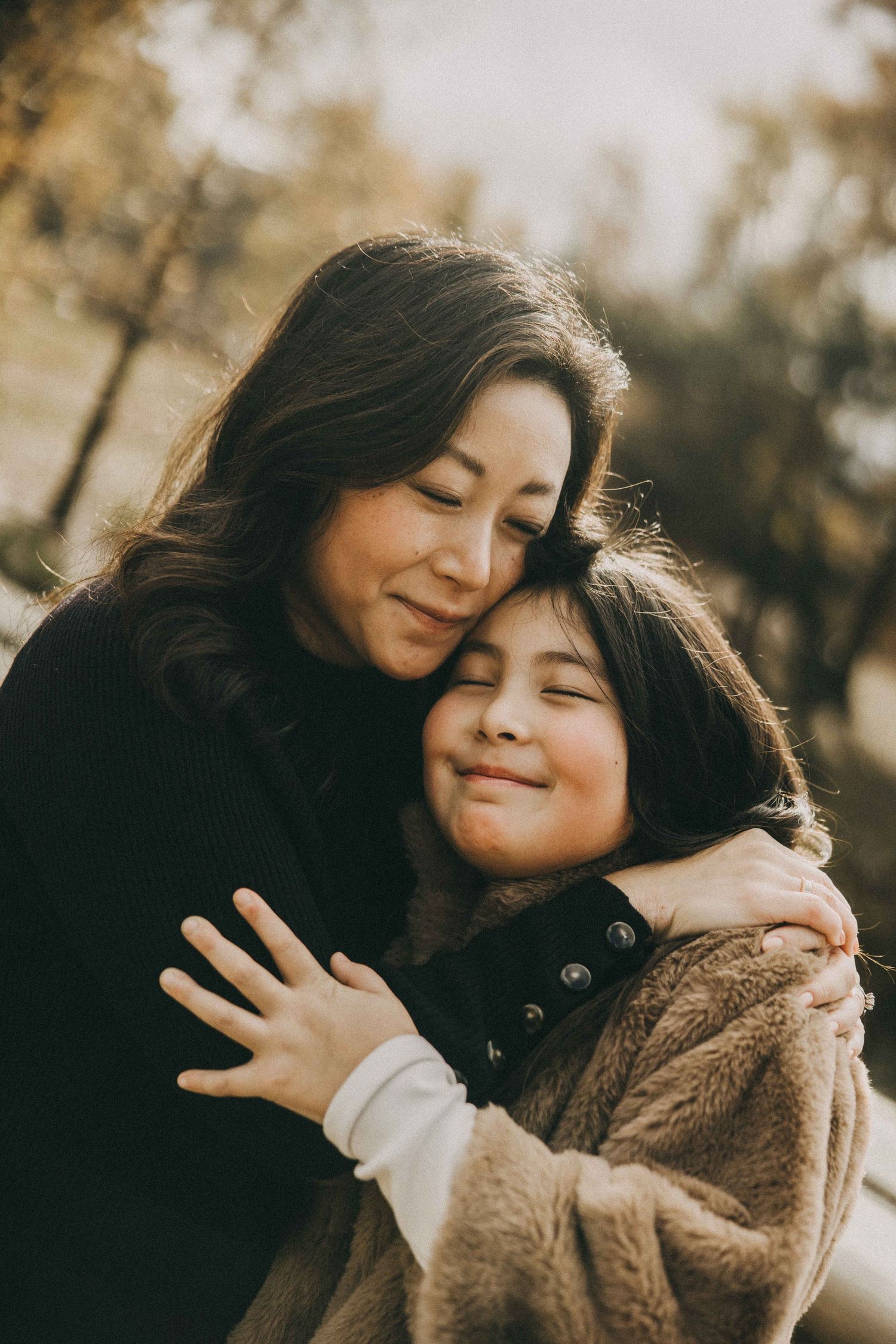 A tender moment captured between parent and child embracing outdoors in warm sunlight.