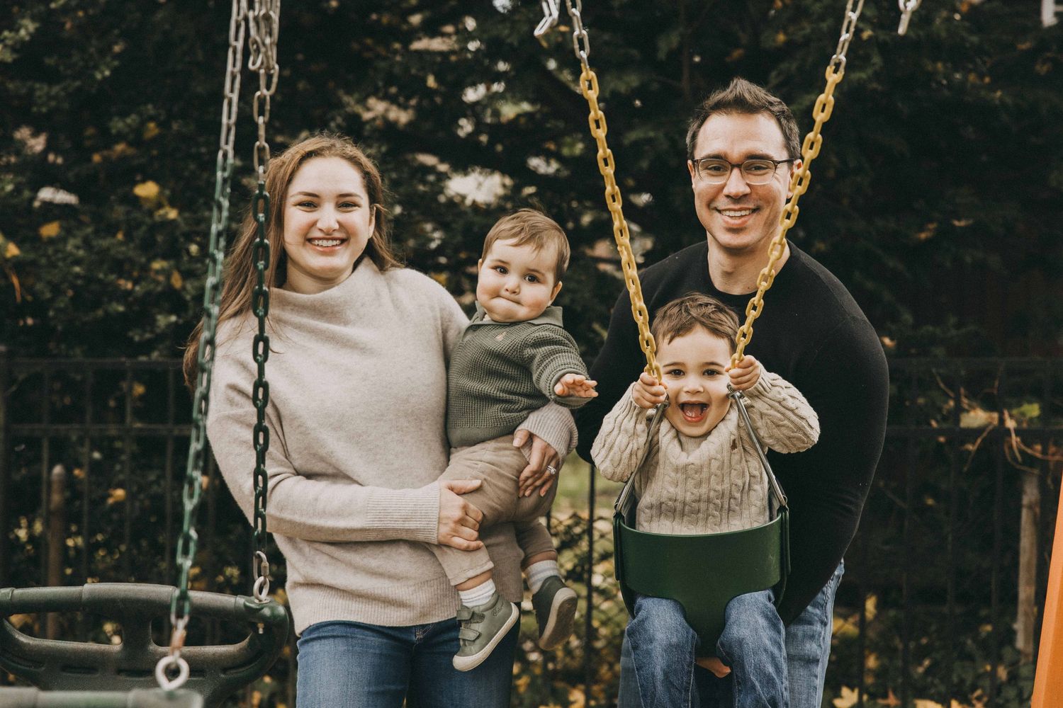 A family enjoys playful moments on outdoor swings in a natural setting during autumn.