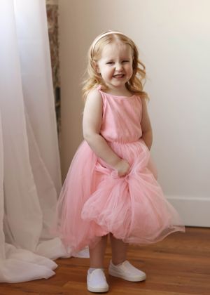 Series showing playful movements in a pink tulle dress on hardwood floor.