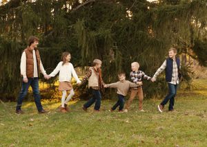 Family members walk in line holding hands during outdoor photo session.
