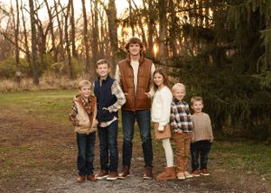 Extended family group portrait taken outdoors with trees and natural lighting.