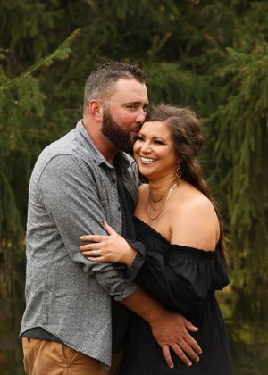 A couple laughs and embraces while sharing intimate moments outdoors.