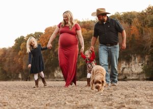 A family walks together on a dirt path during golden hour with warm sunlight filtering through.