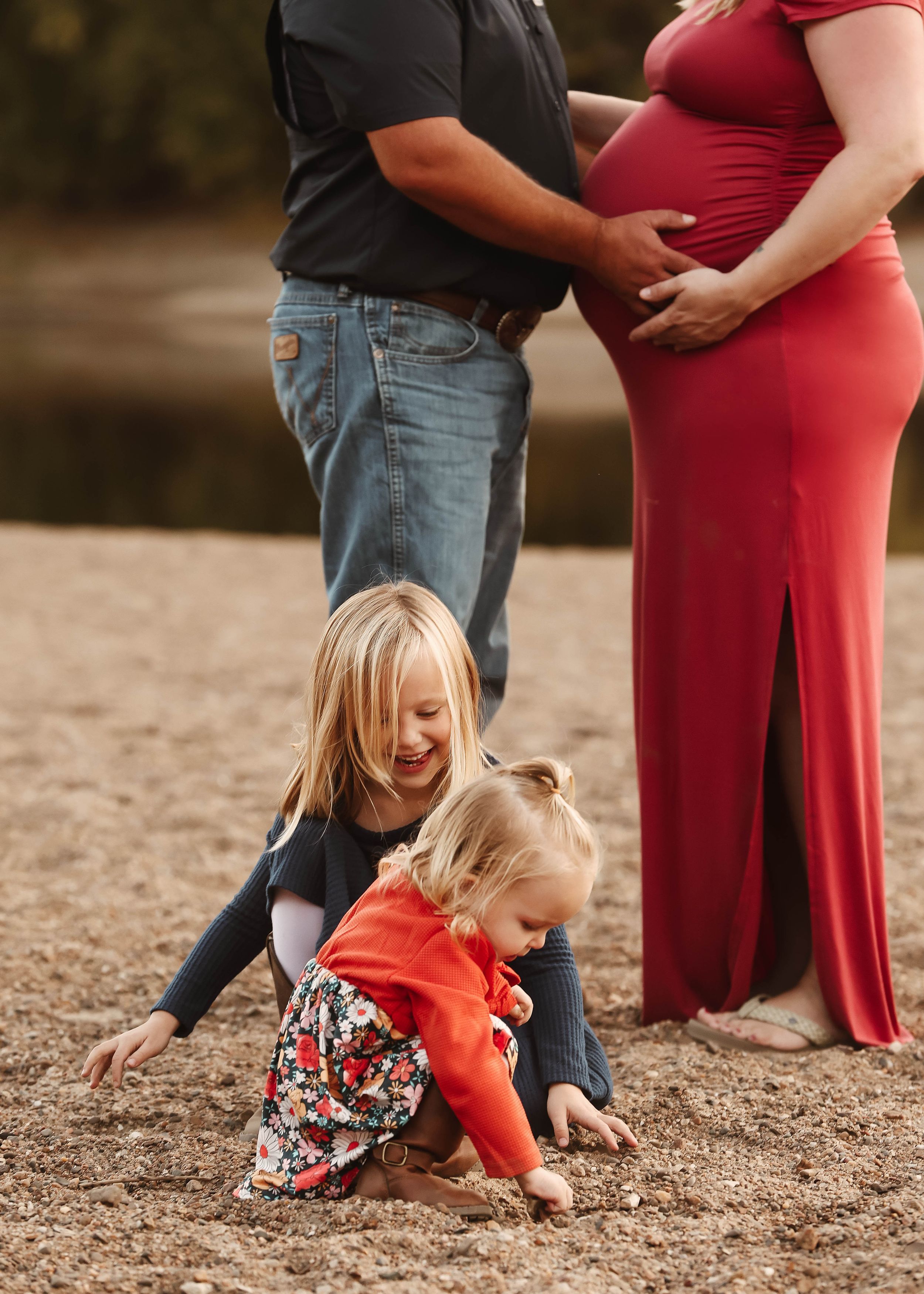 Family spending time together on autumn beach with colorful trees in background.