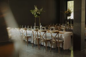 Rustic dining room with cross-back chairs and tables decorated for an elegant wedding reception.
