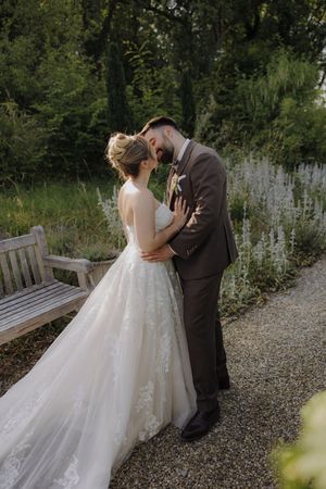 A series of romantic wedding portraits showing a couple in formal attire embracing on a garden path with natural greenery.