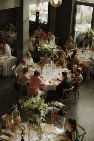 Elegant wedding reception with long tables set with white linens and floral centerpieces in a bright indoor venue.