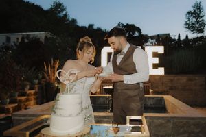 Elegant all-white tiered wedding cake layered with strips of fondant ribbon and floral accents for a modern reception.