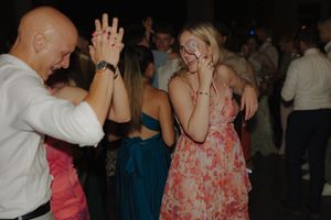 Two people dancing together at a social event with others in the background.