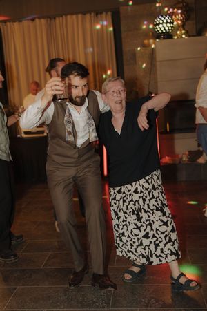 Two people dance energetically on a dim dance floor with decorative lighting in the background.