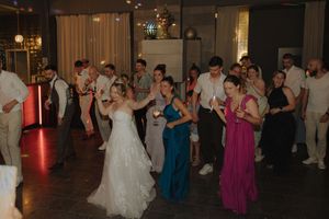 Wedding reception guests dancing and celebrating on a dimly lit dance floor during an evening celebration.