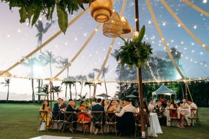 A large clear wedding tent set up on the lawn after sunset at Lanikuhonua Venue, Ko Olina, Oahu, with a beautiful wedding reception.