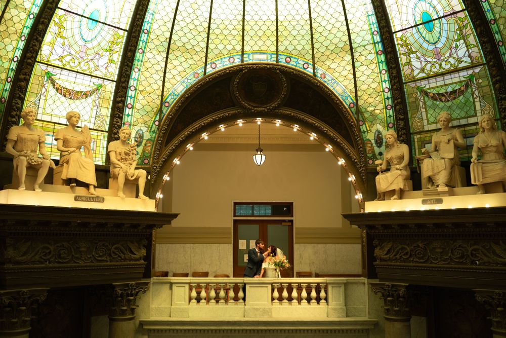 Elegant dome ceiling with stained glass windows and string lights in historic wedding venue.