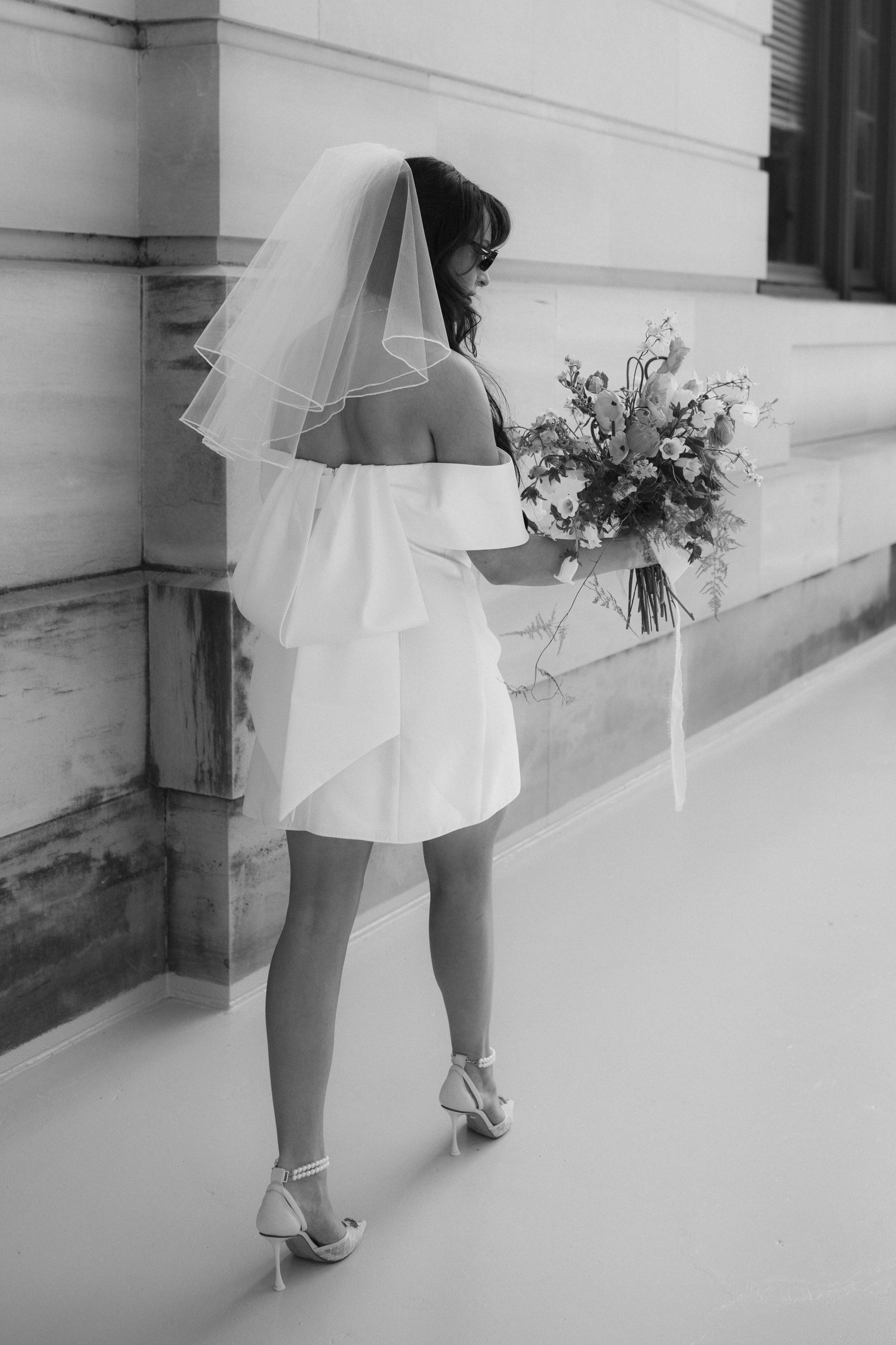 Black and white photos showing details of a short wedding dress, bouquet and bridal shoes.