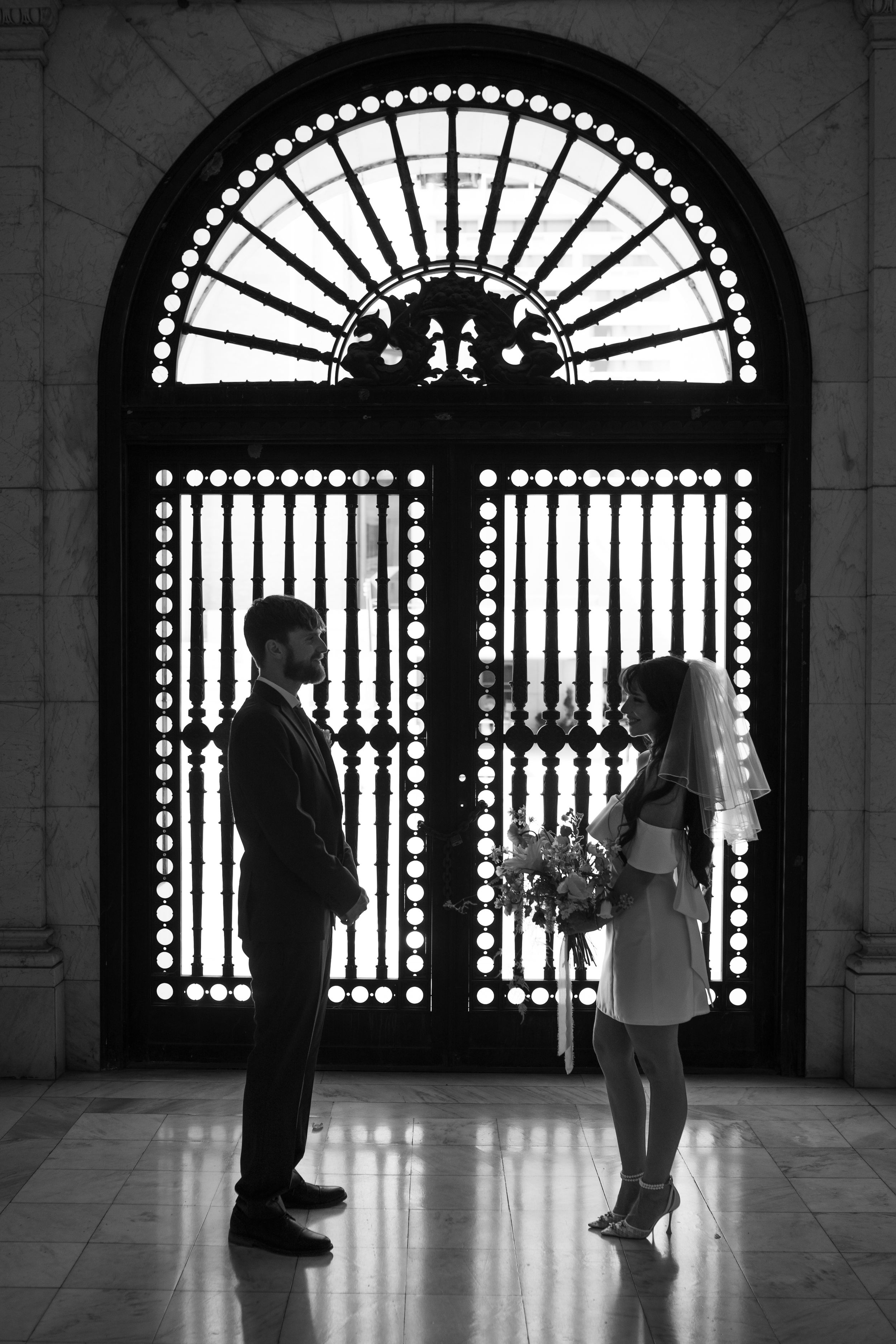 Dramatic black and white silhouettes of a couple against ornate arched doorways.