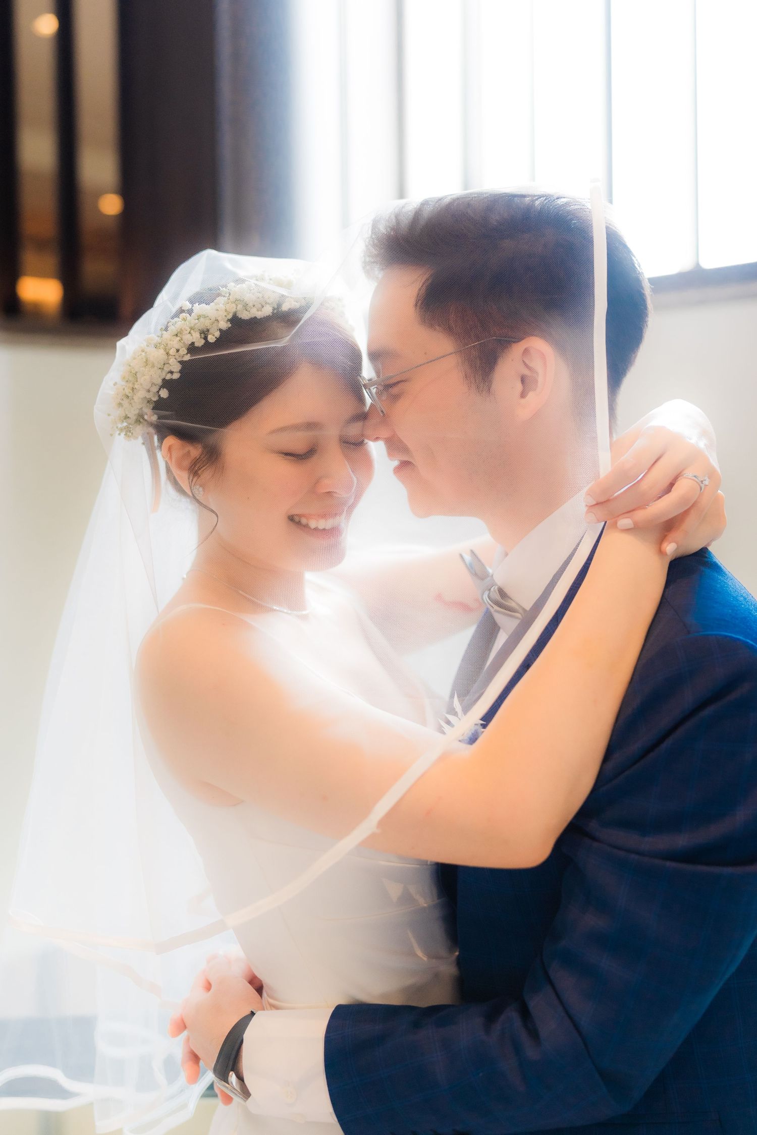 Romantic wedding portrait in soft natural light by a window.