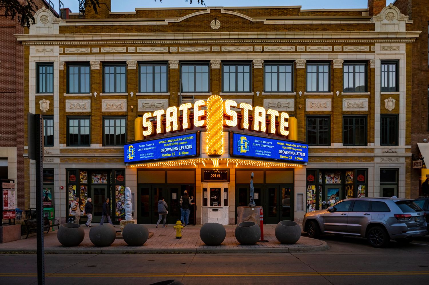 Historic State Theater with illuminated marquee and classical architecture at dusk.