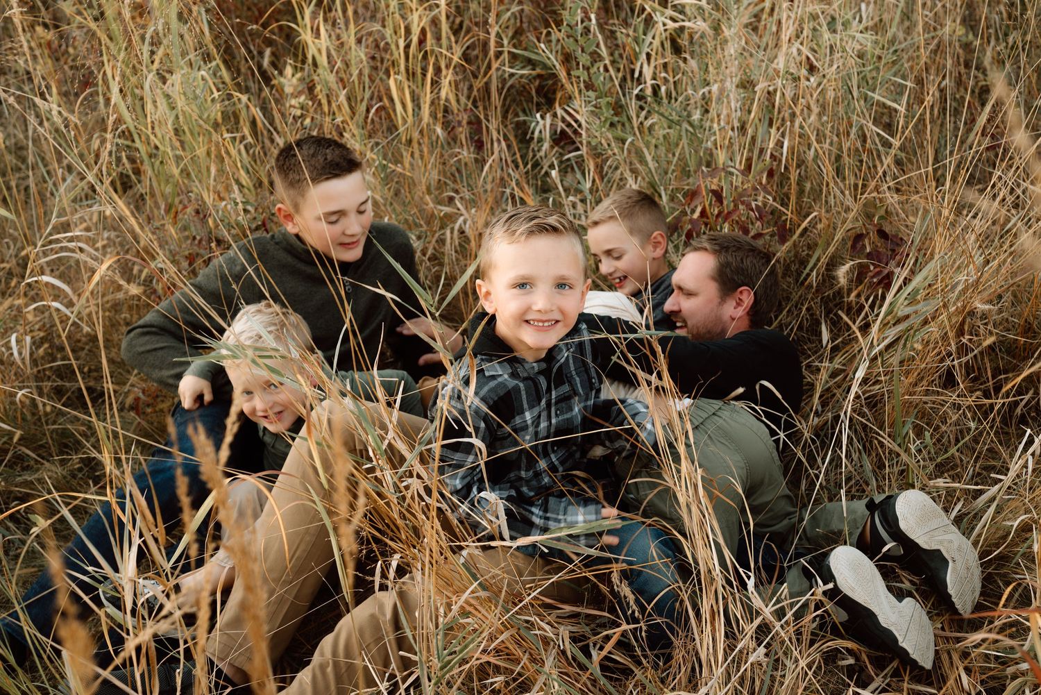 Family portrait on carpet with white pampas grass decor and baby in casual setting.