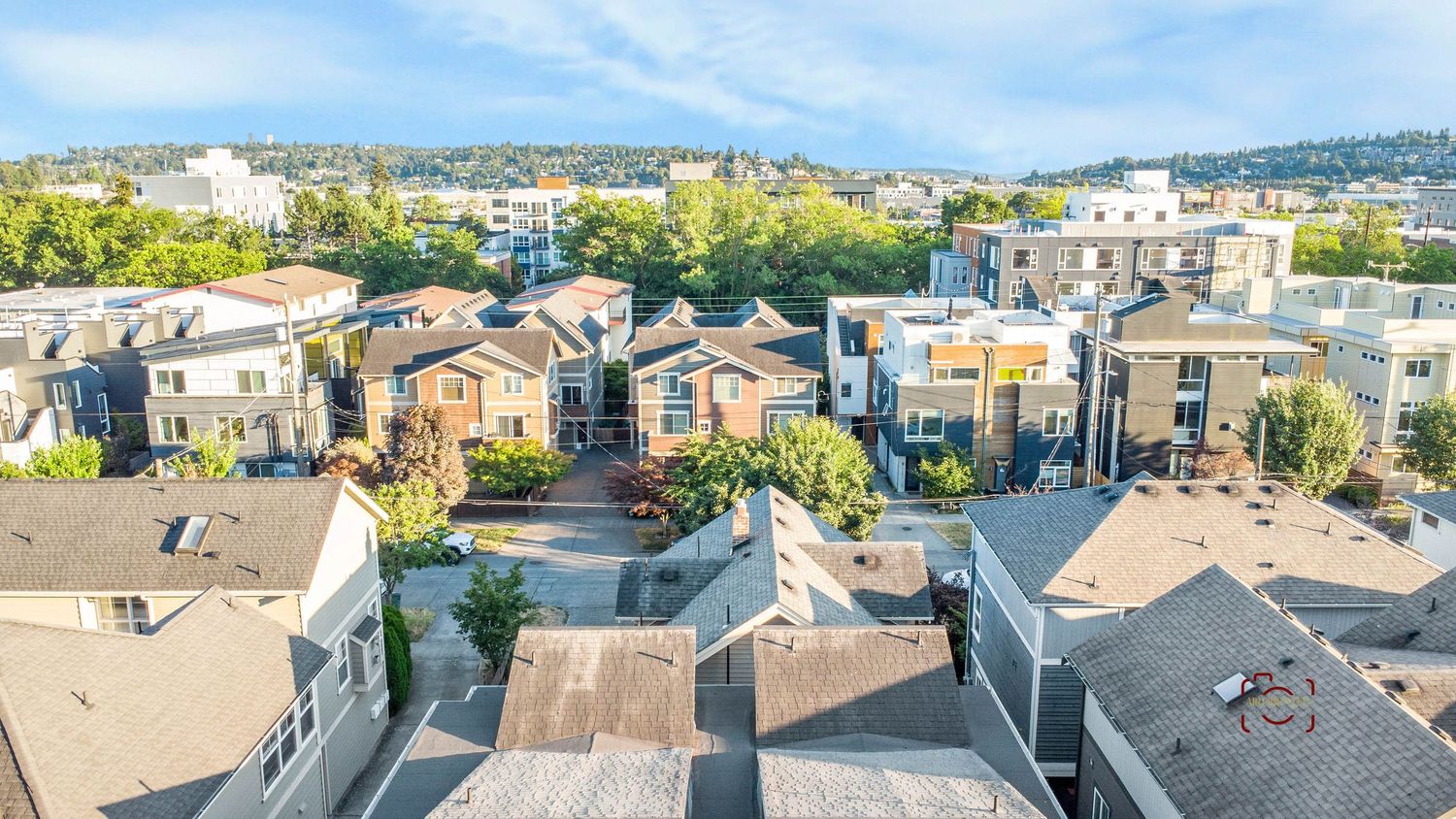 Aerial view of residential neighborhood with modern townhouses and rooftops under blue sky.