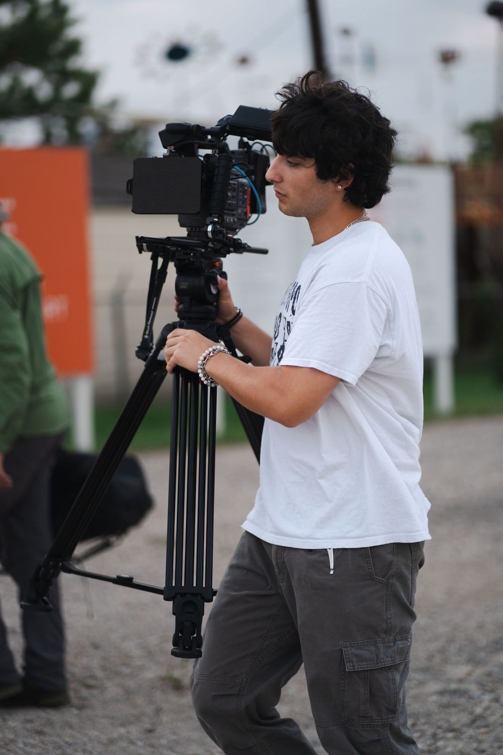 Camera operator adjusts professional video equipment on a tripod during filming.