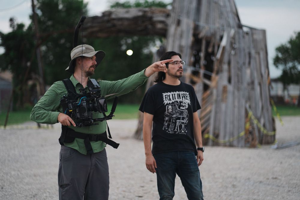 Film crew member points while directing a scene during an outdoor production shoot.