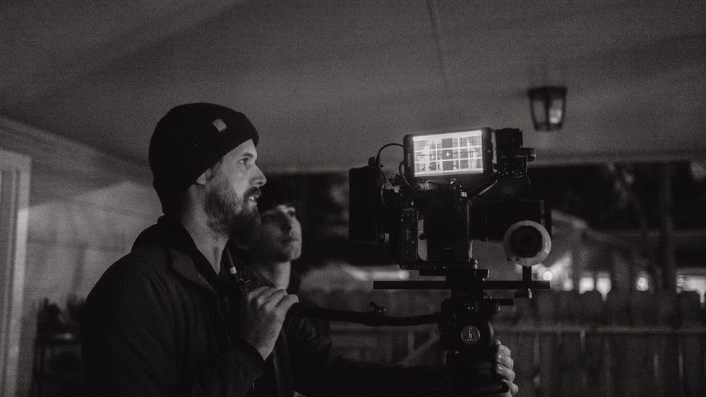 Camera operator framing shot in dark atmospheric setting.