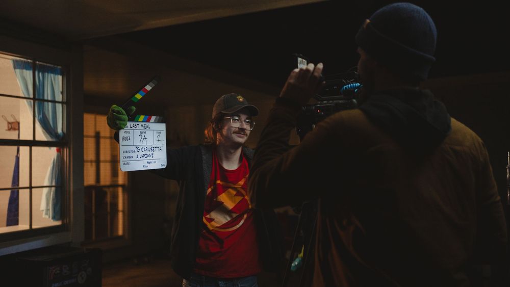 Two crew members review film scene in dark interior setting.