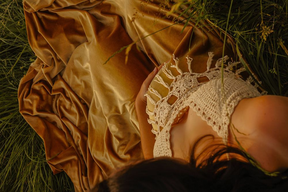 Flowing golden fabric and lace details photographed in tall grass.