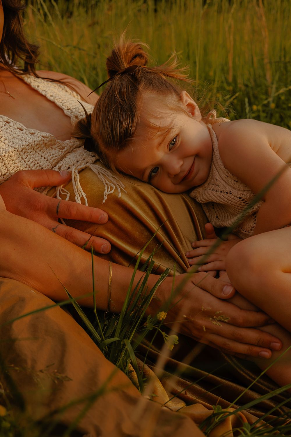 A candid moment of joy captured in tall grass during golden hour.